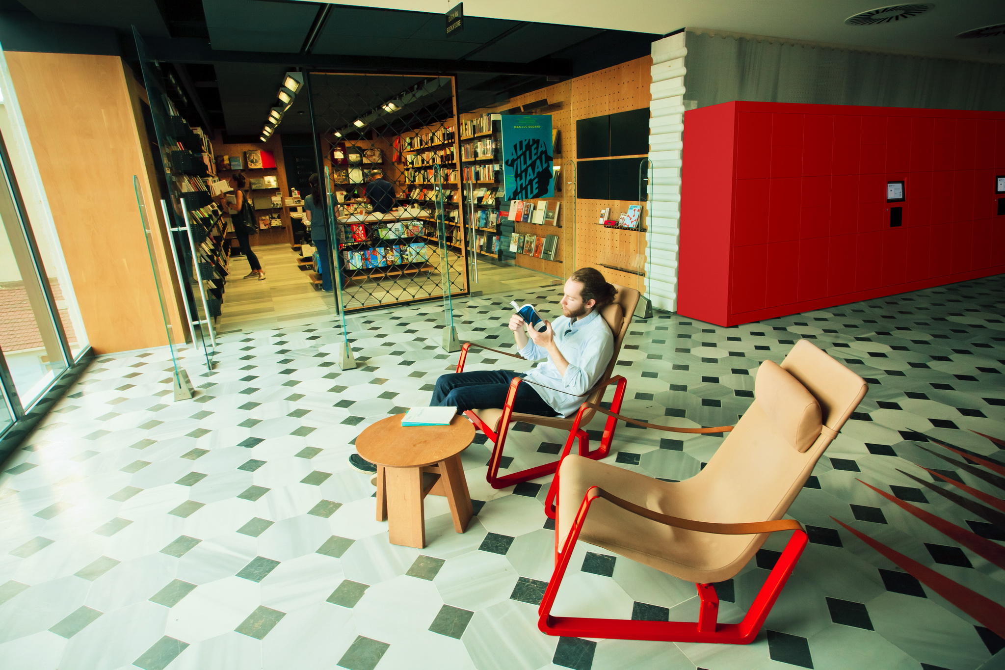 Young man reading a book near bookstore inside modern art gallery